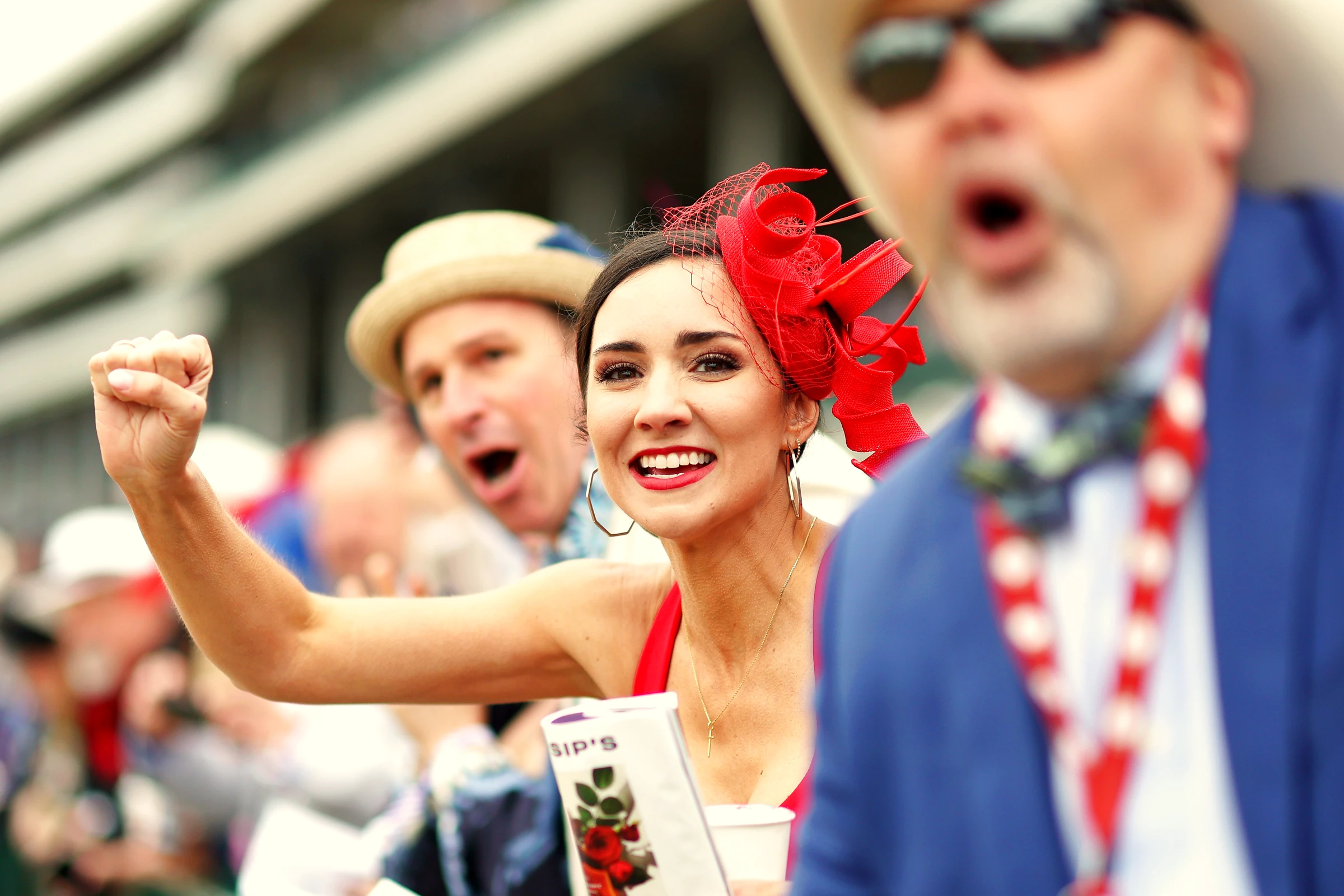 Fans in Derby hats cheering at the rail during a race